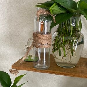 A glass vase with a crystal necklace along with plant trimmings
